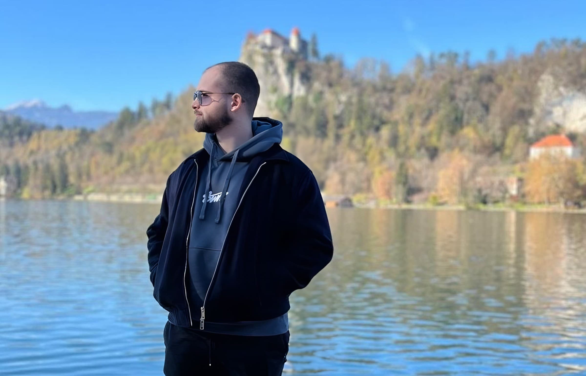 Antonio standing by Lake Bled with the castle on the cliff behind him